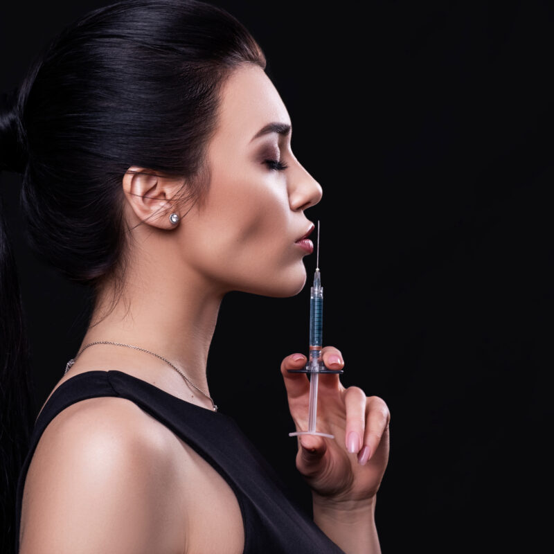 Cosmetology treatment on a brunette caucasian woman face. Fresh, clean skin with flawless features. She holds cosmetology items in her hands.