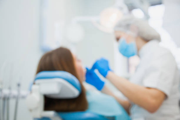 Defocused, blurred image of dentist with patient at clinic office. Stomatologist making tooth treatment at hospital.